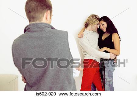 Man watching couple hugging View Large Photo Image Stock Image - Man watching couple hugging. Fotosearch
