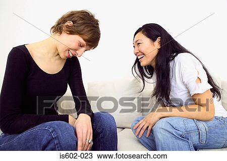 Stock Image - Two women laughing on sofa. Fotosearch