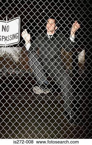 Stock Photo - Businessman climbing a fence. Fotosearch