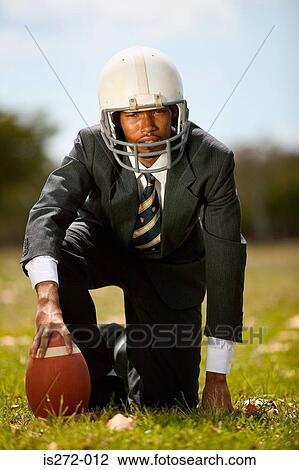 Stock Image - Businessman playing american football. Fotosearch