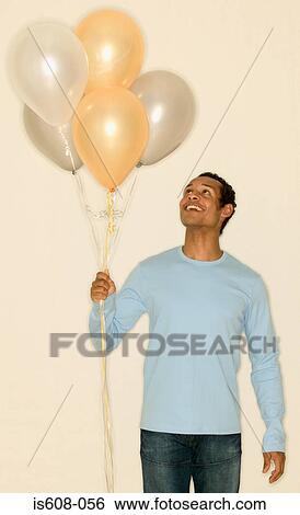 Man holding a bunch of balloons View Large Photo Image Stock Photograph - Man holding a bunch of balloons. Fotosearch