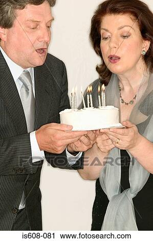 Mature couple blowing out candles on cake View Large Photo Image Stock Image - Mature couple blowing out candles on cake. Fotosearch