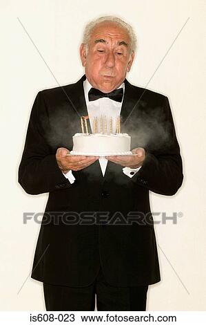 Stock Image - Senior man holding a birthday cake. Fotosearch
