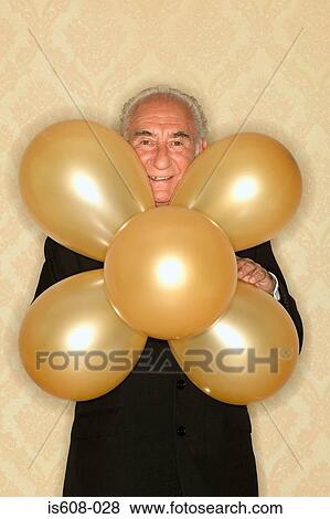Stock Photo - Senior man holding bunch of balloons. Fotosearch
