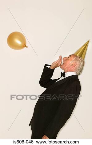 Senior man inflating a balloon View Large Photo Image Stock Photograph - Senior man inflating a balloon. Fotosearch