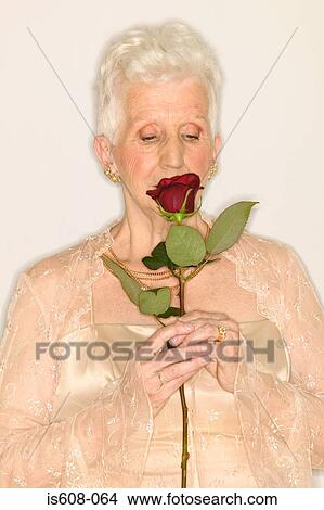 Picture - Senior woman sniffing rose. Fotosearch