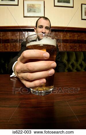 Stock Image - Businessman drinking a pint of lager. Fotosearch