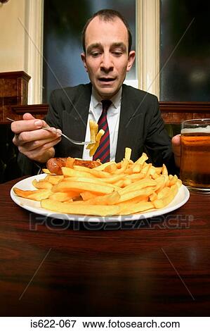 Businessman eating plate of french fries View Large Photo Image Stock Photo - Businessman eating plate of french fries. Fotosearch