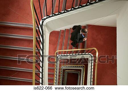 Businessman walking up spiral stairway View Large Photo Image Stock Photograph - Businessman walking up spiral stairway. Fotosearch