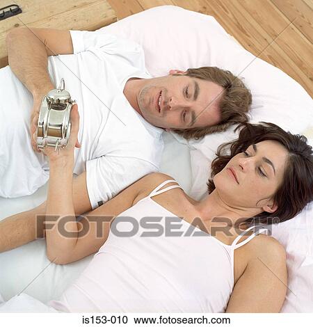 Couple in bed looking at clock View Large Photo Image Stock Image - Couple in bed looking at clock. Fotosearch