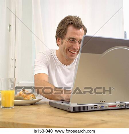 Stock Image - Man at breakfast with laptop. Fotosearch