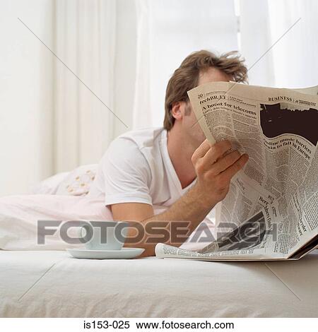 Stock Photography - Man in bed with tea and paper. Fotosearch