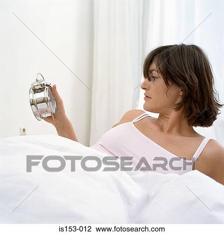 Woman in bed looking at clock View Large Photo Image Stock Image - Woman in bed looking at clock. Fotosearch