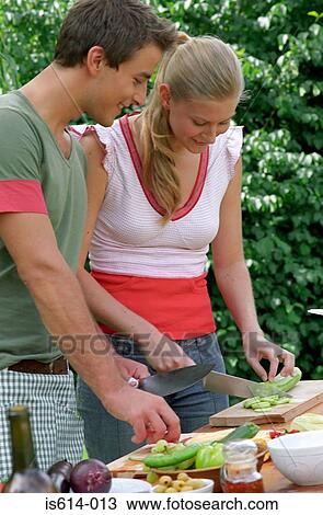 Stock Image - Couple prepare meal outdoors. Fotosearch