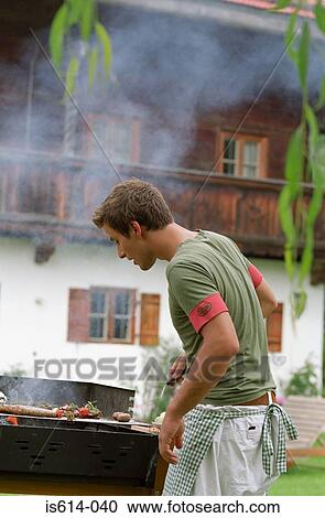 Young male cooks on barbeque View Large Photo Image Stock Image - Young male cooks on barbeque. Fotosearch