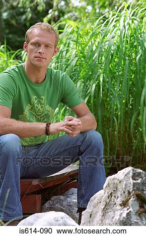 Stock Image - Young man sitting outdoors.. Fotosearch