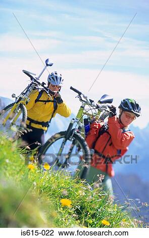 Stock Image - Carrying bikes across hillside.. Fotosearch