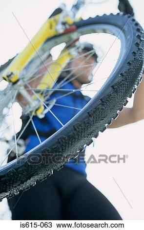 Stock Image - View of cyclist through spokes.. Fotosearch