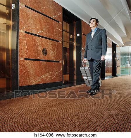 Businessman with wheeled suitcase View Large Photo Image Stock Photograph - Businessman with wheeled suitcase. Fotosearch