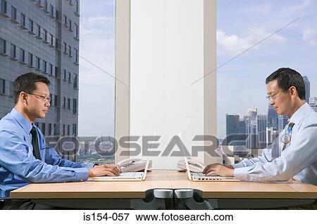 Stock Photo - Businessmen using laptop computers. Fotosearch