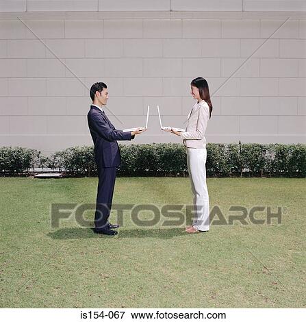 Young businesspeople holding laptop computers View Large Photo Image Stock Photo - Young businesspeople holding laptop computers. Fotosearch