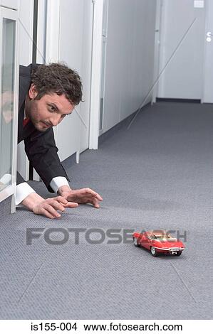 Businessman playing with toy car View Large Photo Image Picture - Businessman playing with toy car. Fotosearch