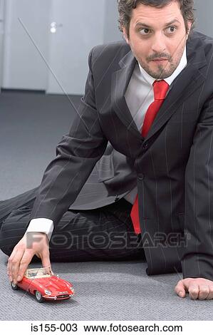 Businessman playing with toy car View Large Photo Image Stock Image - Businessman playing with toy car. Fotosearch