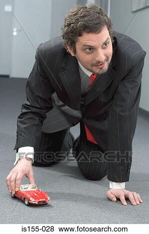 Businessman playing with toy car View Large Photo Image Stock Photo - Businessman playing with toy car. Fotosearch