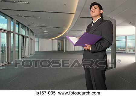 Businessman standing in empty office View Large Photo Image Stock Photography - Businessman standing in empty office. Fotosearch