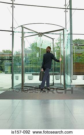 Businesswoman walking through revolving door View Large Photo Image Stock Image - Businesswoman walking through revolving door. Fotosearch