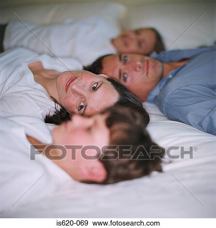 Family relaxing on bed View Large Photo Image Stock Photo - Family relaxing on bed. Fotosearch