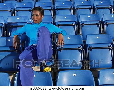 Stock Image - Athlete sitting in empty stadium. Fotosearch