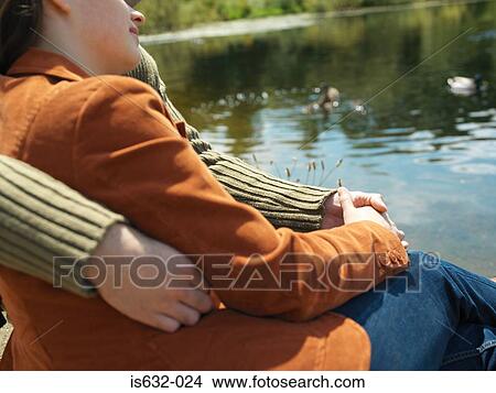 Picture - Couple sitting near lake. Fotosearch