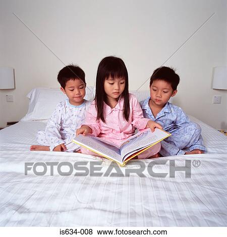 Stock Photo - Children on bed reading book. Fotosearch