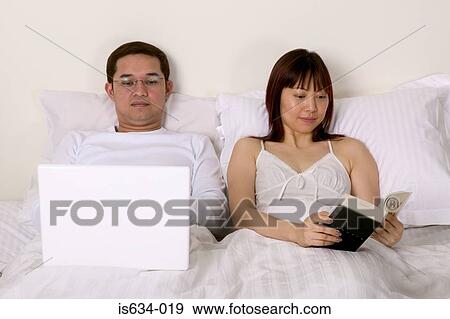 Couple in bed reading View Large Photo Image Stock Photo - Couple in bed reading. Fotosearch