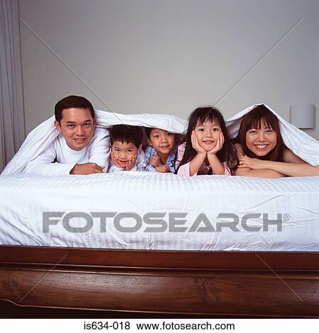 Stock Photo - Happy young family in bed. Fotosearch