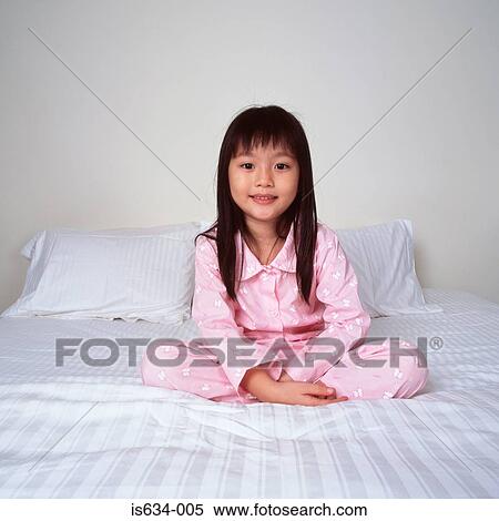 Stock Photography - Smiling young girl on bed. Fotosearch