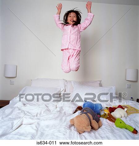 Young girl jumping on bed View Large Photo Image Stock Image - Young girl jumping on bed. Fotosearch