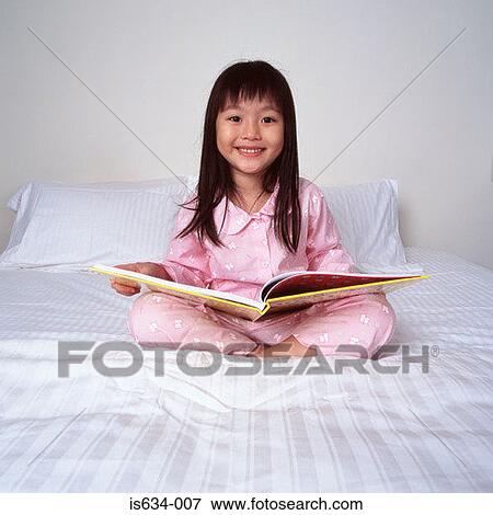 Stock Photo - Young girl on bed with book. Fotosearch