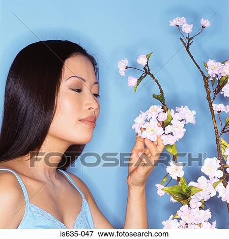 Stock Photo - Young woman sniffing blossom. Fotosearch