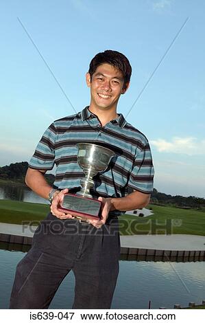 Asian man holding a trophy View Large Photo Image Stock Photo - Asian man holding a trophy. Fotosearch