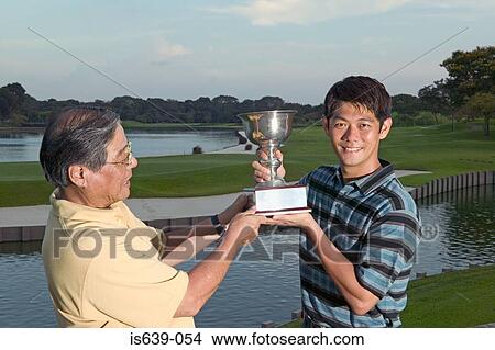 Father and son holding trophy View Large Photo Image Picture - Father and son holding trophy. Fotosearch
