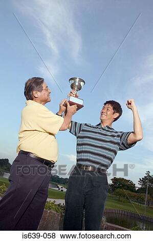 Father and son holding trophy View Large Photo Image Stock Photo - Father and son holding trophy. Fotosearch