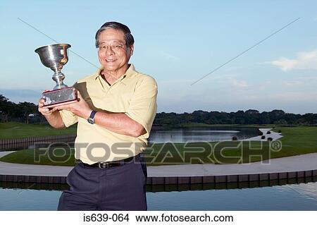 Male golfer holding trophy View Large Photo Image Picture - Male golfer holding trophy. Fotosearch