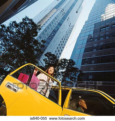 Stock Photography - Woman leaving taxicab with shopping bags. Fotosearch