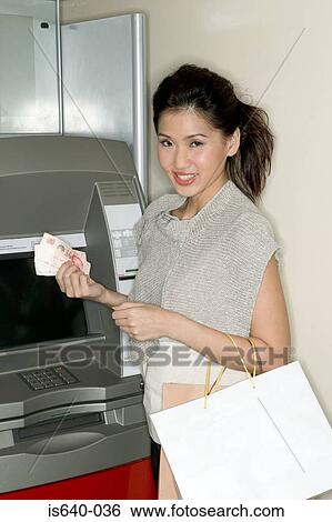 Stock Photograph - Woman using a cash machine. Fotosearch