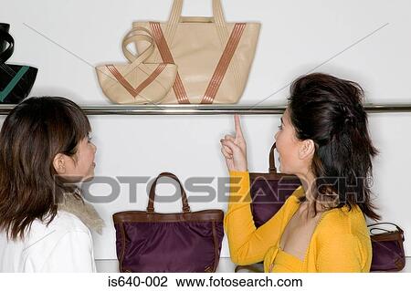 Stock Image - Women shopping for handbags. Fotosearch