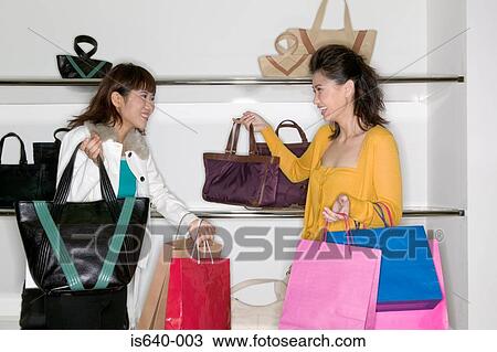 Stock Image - Women shopping for handbags. Fotosearch
