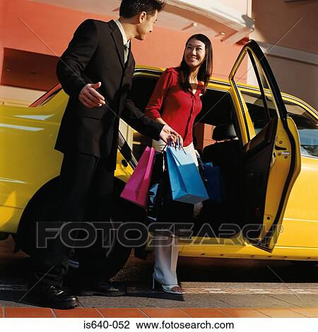 Stock Image - Young couple leaving taxicab. Fotosearch