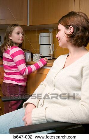 Stock Image - Disabled mother and daughter in kitchen. Fotosearch
